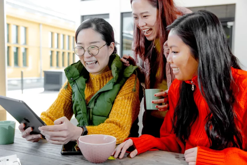 Drei Frauen schauen auf ein Tablet und lachen