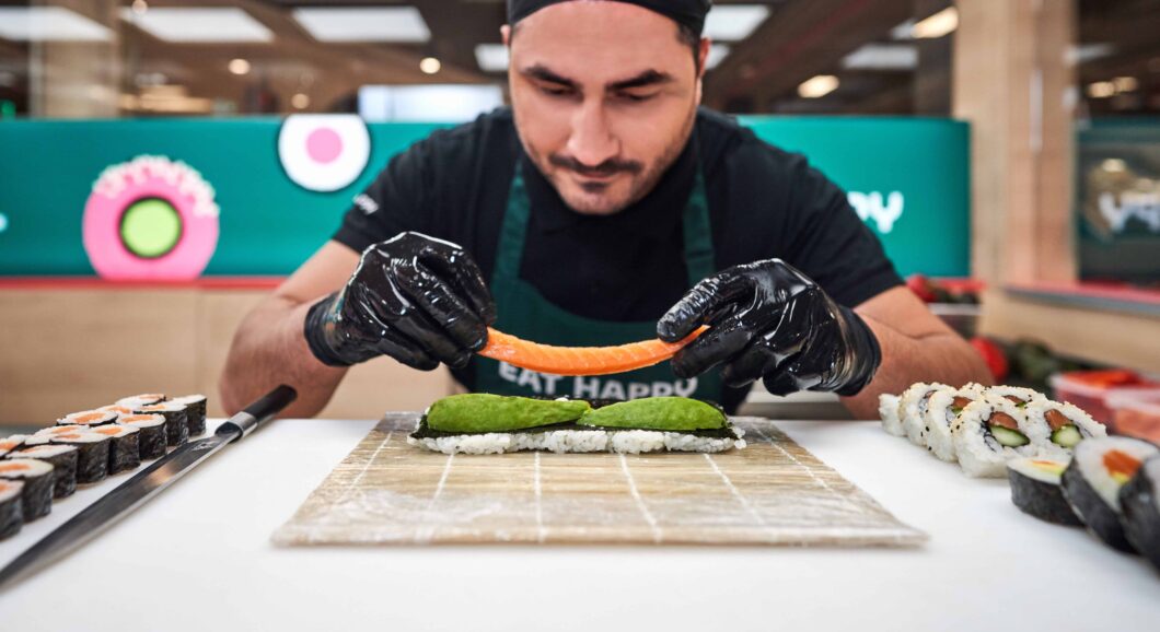 Sushikoch bereitet eine Sushirolle sehr präzise vor